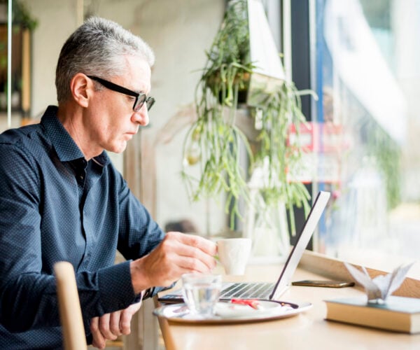 Man drinking coffee and working on a computer