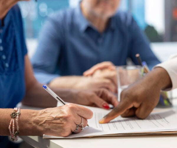 Close up image of hands signing paperwork